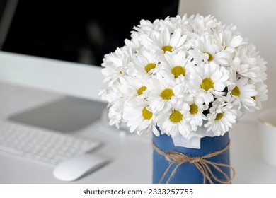 Beautiful bouquet of chamomile flowers on office desk near computer - Powered by Shutterstock