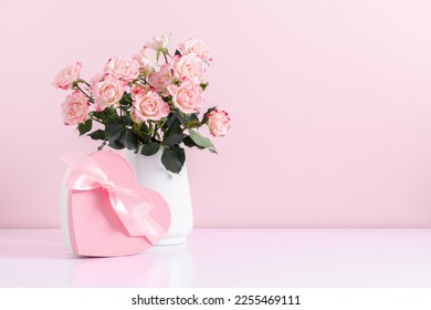 Beautiful bouquet flowers pink roses in vase and  gift box with satin bow on pastel pink background table. Birthday, Wedding, Mother's Day, Valentine's day, Women's Day. Front view - Shutterstock ID 2255469111