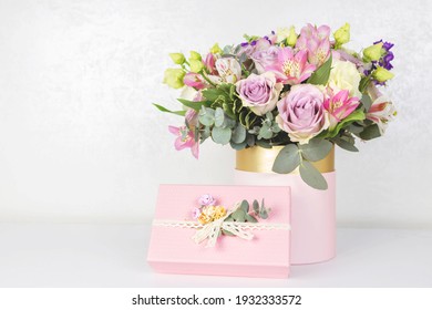 Beautiful bouquet of flowers in round box and pink gift box on a white table. Gift for holiday, birthday, Wedding, Mother's Day, Valentine's day, Women's Day. Floral arrangement in a hat box. - Shutterstock ID 1932333572