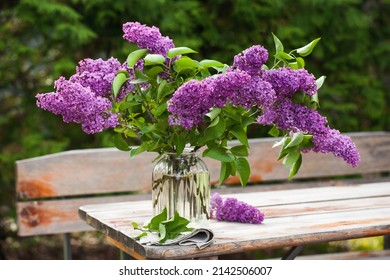 Beautiful bouquet of lilacs in a vase on a wooden table in nature.