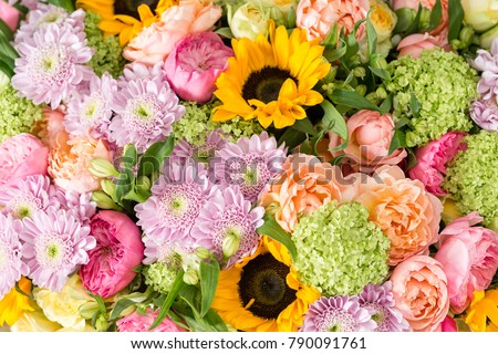 beautiful bouquet of mixed flowers in a vase on wooden table. the work of the florist at a flower shop. a bright mix of sunflowers, chrysanthemums and roses. background on full screen