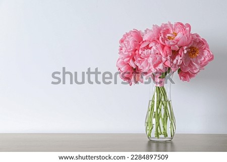 Beautiful bouquet of pink peonies in vase on table against white background. Space for text