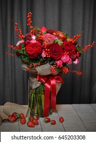 A beautiful bouquet of red roses with strawberries and red apples