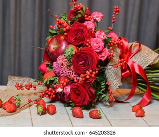 A beautiful bouquet of red roses with strawberries and red apples