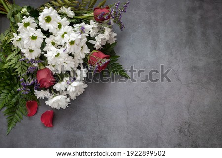 A beautiful bouquet of white chrysanthemums and red roses on a dark background. Top view, copy space