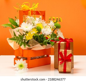 Beautiful Bouquet Of Yellow And White Flowers In The Wooden Basket With Gift Boxes.