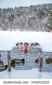 Beautiful boy bathing and swimming in the cold water of a lake or river among the ducks, cold therapy, ice swim with forest trees on background, vertical