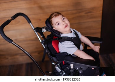 beautiful boy child in a special wheelchair. Toddler with cerebral palsy. Rehabilitation process at home indoor. Lifestyle moments. 
