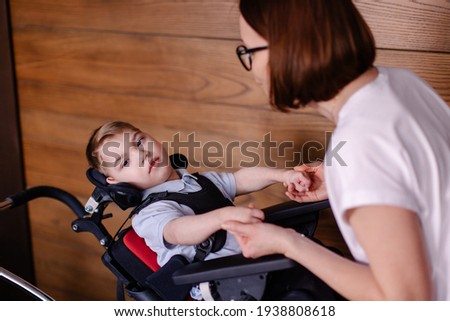 beautiful boy child in a special wheelchair. Toddler with cerebral palsy with his mother. Rehabilitation with a teacher is a process. Lifestyle moments. Rehabilitation therapist lesson therapy