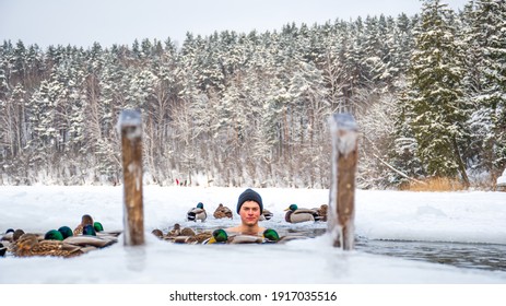 Beautiful boy with hat bathing and swimming in the cold water of a lake or river among the ducks, cold therapy, ice swim with forest trees on background