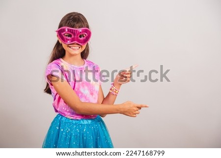 Beautiful Brazilian girl, child, dressed for carnival in Brazil. with carnival mask, presenting product on the side.