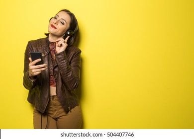 Beautiful Brazilian Girl Enjoying Music With The Head Phones In Yellow Background