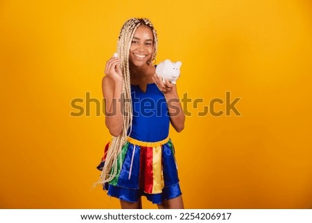 beautiful  brazilian woman with braids, wearing clothes for carnival. Holding coin and piggy bank.