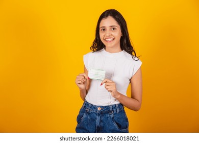 beautiful brazilian woman holding voter registration card.