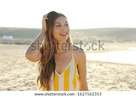 Beautiful brazilian woman in summer dress on tropical beach. Portrait of happy young woman smiling at sea.