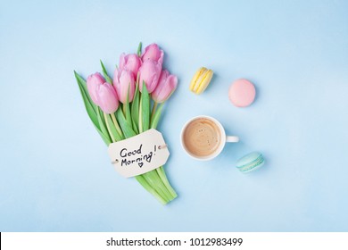 Beautiful breakfast on Mothers or Womans day. Coffee cup with pink tulip flowers, macaroon and note good morning on blue table top view.  - Powered by Shutterstock