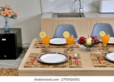 Beautiful breakfast table setup featuring fresh orange juice with lemon slices, a vibrant fruit bowl filled with apples, pears, and grapes, elegant plates, and rustic wooden placemats. Perfect for home decor and dining inspiration.