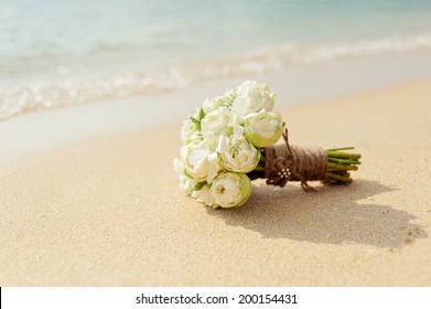 Beautiful bridal bouquet of white lotuses and orchids on a tropical beach.