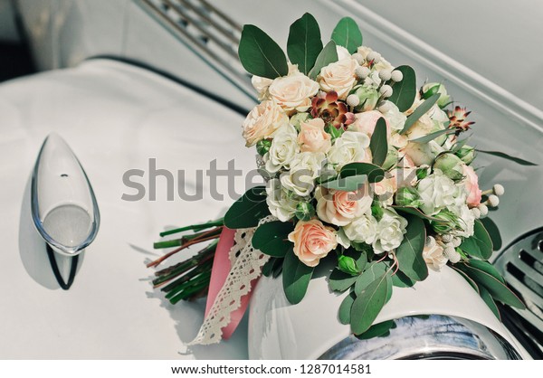 Beautiful bridal flower\
bouquet in a stylish white retro car. Accessories and elements of\
the wedding day