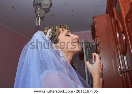 Beautiful bride applying perfume on her neck on wedding morning, Side view of bride spraying luxury perfume close up