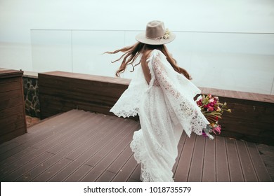 Beautiful Bride In Bohemian Wedding Dress And Hat With Bouquet