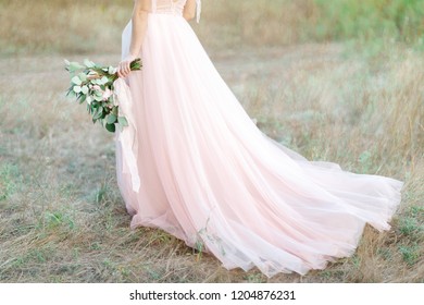 Beautiful bride with bouquet and dress with train in the nature. fine art photography.