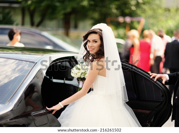 Beautiful bride\
with bouquet of flowers in the car\
