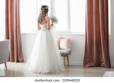 Beautiful bride with bouquet of flowers near window