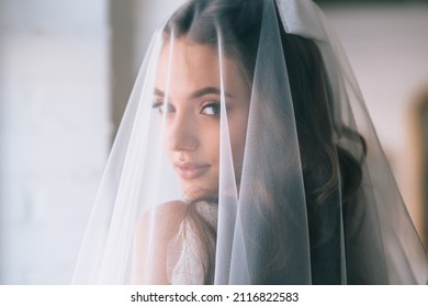 Beautiful bride with fashion wedding hairstyle . Closeup portrait of young gorgeous bride. Wedding. Studio shot.Beautiful bride portrait with veil over her face