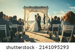 Beautiful Bride and Groom During an Outdoors Wedding Ceremony on a Beach Near the Ocean. Perfect Venue for Romantic Couple to Get Married, Kiss and for Friends with Multiethnic Cultures to Celebrate.