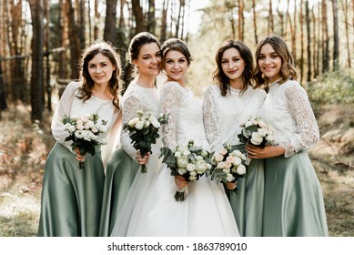 Beautiful bride with her pretty bridesmaids,bridesmaids with a bride hugging and laughing cheerfully, happy wedding day, wedding bouquet, holiday of newlyweds