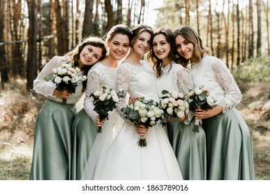 Beautiful bride with her pretty bridesmaids,bridesmaids with a bride hugging and laughing cheerfully, happy wedding day, wedding bouquet, holiday of newlyweds
