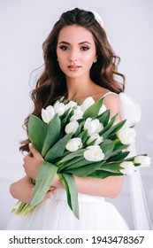 Beautiful bride holding wedding bouquet of white tulips in her hands in studio. Wediing day