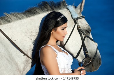 Beautiful bride with the horse on the sea shore. Horsewoman