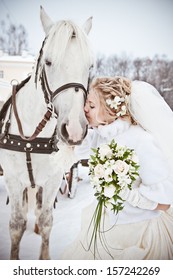 The beautiful bride with a horse in a winter park