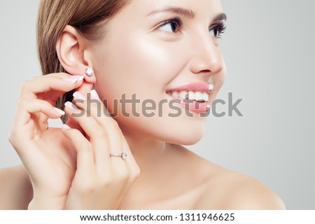 Beautiful bride in puts on diamond earring. Beauty model girl in wedding jewelry, perfect face closeup