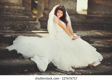 Beautiful bride sits on the stairs of  the old church