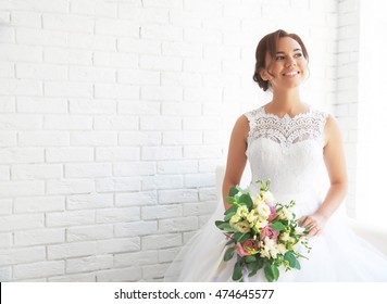 Beautiful bride with wedding bouquet on white brick wall background - Powered by Shutterstock