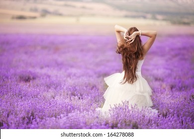 Beautiful Bride in wedding day in lavender field. Newlywed woman in lavender flowers. Young woman in wedding dress outdoors.