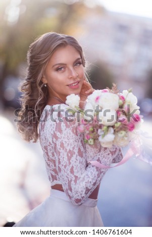 Beautiful bride in a wedding dress with a bouquet of flowers posing on the street