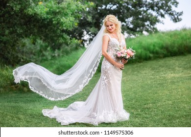 beautiful bride in wedding dress with long veil fluttering in the wind outdoors