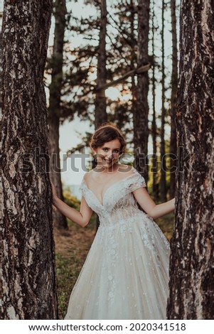 a beautiful bride in a wedding dress poses in the forest on her wedding day. Selective focus 
