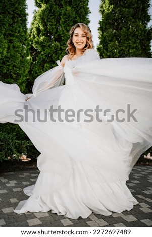 beautiful bride in a white delicate dress dances and spins in the park. the concept of wedding fashion and organization of ceremonies in the fresh air. staging and rehearsal of the wedding dance