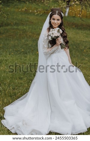 a beautiful bride in a white dress with a bouquet of flowers in her hand walks on the green grass in the garden. Portrait of the bride in the spring garden