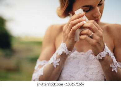 Beautiful Bride In White Dress Weeps Tears Of Happiness On The Wedding Day. Emotional Woman In Wedding Gown Wipes The Tears With Tissue Paper.