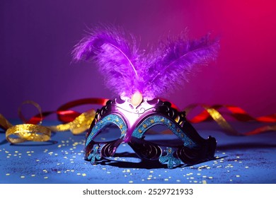 Beautiful bright carnival mask, ribbons and confetti on color background