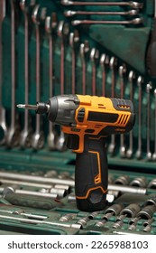 a beautiful bright cordless electric screwdriver with a phillips bit stands on a case with a tool, with open-end wrenches, bits, heads