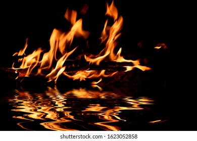 Beautiful Bright Flame From A Fire On A Black Background With Reflection In The Water