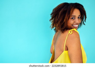 Beautiful bright joyful african woman in yellow dress in blue studio background - Shutterstock ID 2232892815