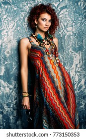 Beautiful bright woman with curly foxy hair wears a dress and beads in boho style. Ethnic style in clothes.